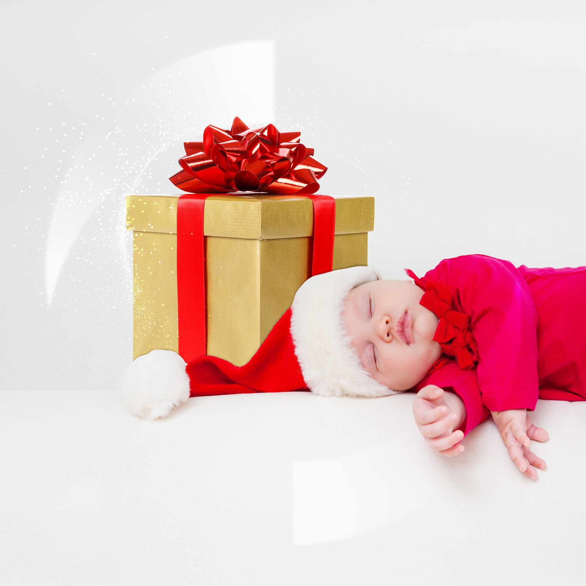 A baby sleeping next to a wrapped gift