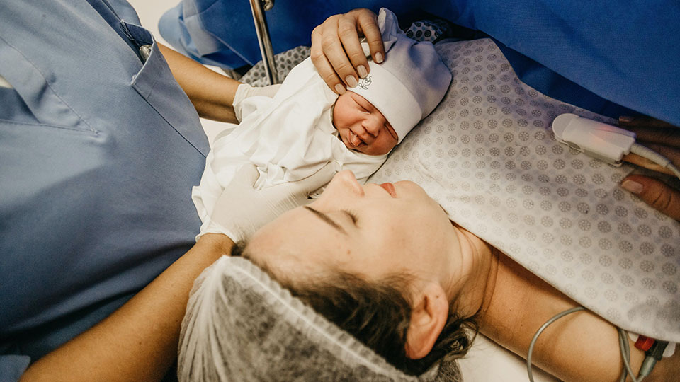 woman holding her baby after gicing birth